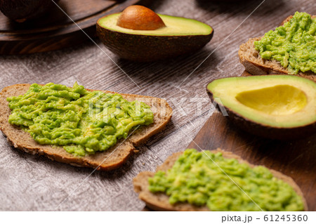 Avocado sandwiches next to cutted ones on wooden board 61245360
