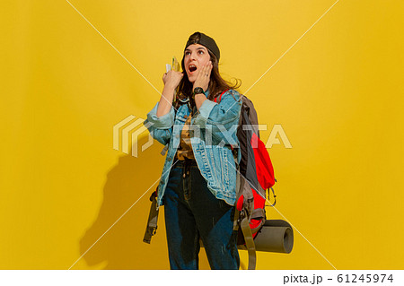 Portrait of a cheerful young caucasian tourist girl isolated on yellow background 61245974