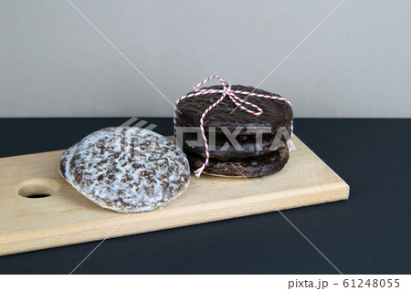 Chocolate ginger biscuits laid out on a wooden board, which stands on a black table Chocolate ginger biscuits laid out on a wooden board, which stands on a black table 61248055