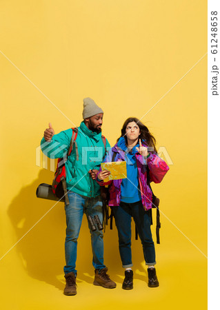 Portrait of a cheerful young tourist couple isolated on yellow background 61248658