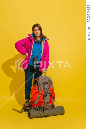 Full length portrait of a cheerful young caucasian tourist girl isolated on yellow background Full length portrait of a cheerful young caucasian tourist girl isolated on yellow background 61249485