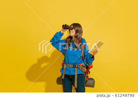Full length portrait of a cheerful young caucasian tourist girl isolated on yellow background 61249798