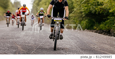 group cyclists riders riding on gravel road group cyclists riders riding on gravel road 61249985