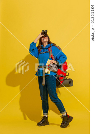 Full length portrait of a cheerful young caucasian tourist girl isolated on yellow background Full length portrait of a cheerful young caucasian tourist girl isolated on yellow background 61251134