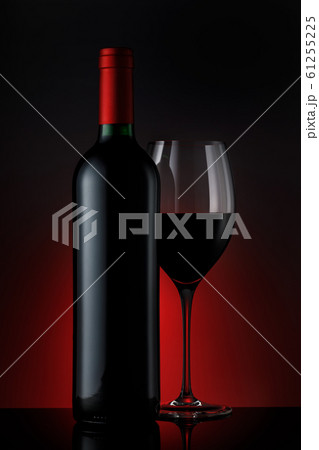 Bottle of red wine with a glass on a black 61255225