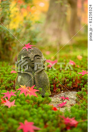 Red Maple leaf on head of Jizo sculpture doll 61256324