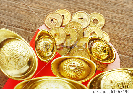 Closeup topview coins spread out from red envelope with group of gold bars on wood table, chinese new year concept Closeup topview coins spread out from red envelope with group of gold bars on wood table, chinese new year concept 61267590