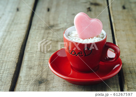 Pink heart shape on red coffee cup with wood table background ,vintage love concept. Pink heart shape on red coffee cup with wood table background ,vintage love concept. 61267597
