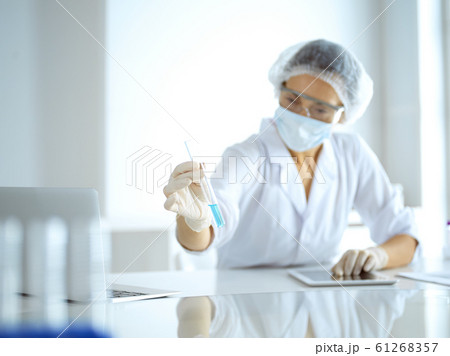 Professional female scientist in protective eyeglasses researching tube with reagents in laboratory. Concepts of medicine and research Professional female scientist in protective eyeglasses researching tube with reagents in laboratory. Concepts of medicine and research 61268357