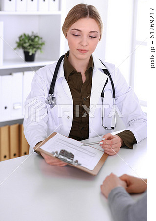 Young woman doctor and patient at medical examination in hospital office. Khaki colored blouse of therapist looks good. Medicine, healthcare and doctor's appointment concept 61269217