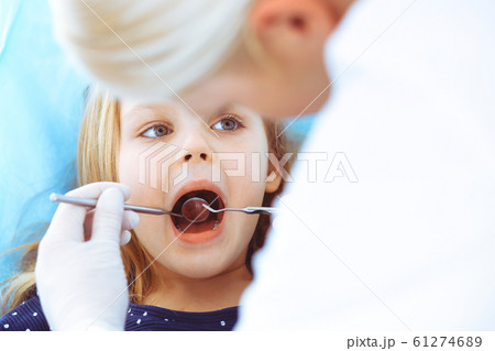 Little baby girl sitting at dental chair with open mouth during oral check up while doctor. Visiting dentist office. Medicine concept. Toned photo 61274689