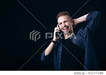 Smiling Youngster Talking on Smartphone and Stretching Himself Smiling Youngster Talking on Smartphone and Stretching Himself 61277180