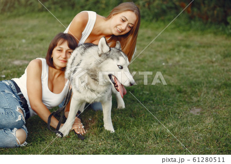 Two girls in a spring park playing with cute dog Two girls in a spring park playing with cute dog 61280511