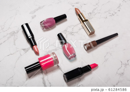 Cosmetic products on marble texture. Lipsticks, nail varnish, makeup brushes on white marble background 61284586