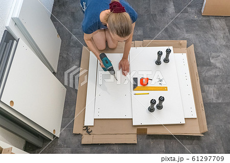Female with a cordless driver collects furniture. Female with a cordless driver collects furniture. 61297709