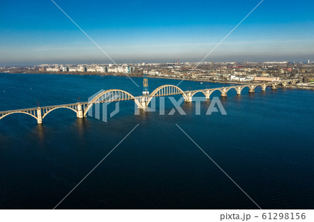 Aerial panoramic view on old arch railway Merefo-Kherson bridge across the Dnieper river in Dnepropetrovsk. View of the left bank of Dnipro city. 61298156