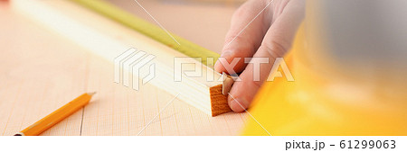 Arms of worker measuring wooden bar closeup 61299063