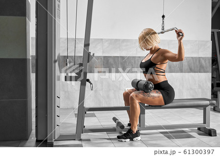Female bodybuilder training back on simulator. 61300397