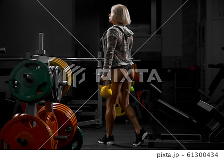Female bodybuilder holding weights in gym. 61300434