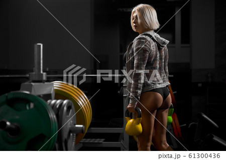 Female bodybuilder in sweatshirt holding weights. 61300436
