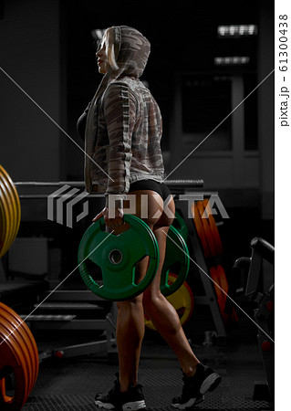 Female bodybuilder in sweatshirt holding weights. 61300438