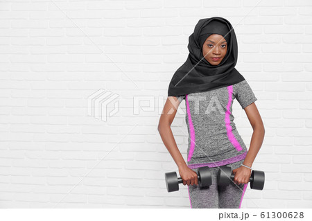 Slim african muslim woman with dumbbells. Slim african muslim woman with dumbbells. 61300628