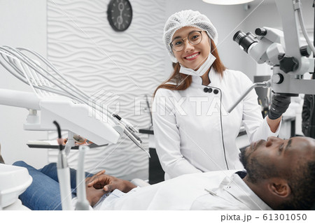Female dentist posing while curing teeth in clinic 61301050