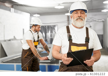 Male engineer in uniform and helmet keeping folder 61301222