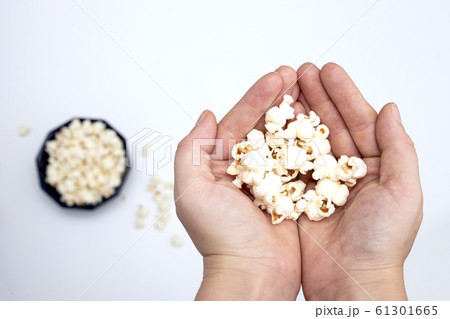 Person holding popcorn in hand top view, with popcorn in bowl isolated on white background 61301665