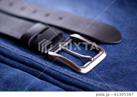 Leather belt lies on denim. Belt accessory Leather belt lies on denim. Belt accessory 61305367