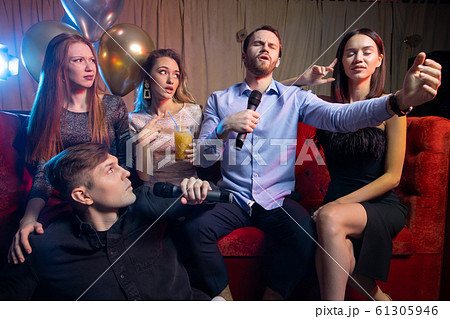 group of young people singing into microphone in karaoke bar group of young people singing into microphone in karaoke bar 61305946