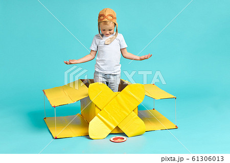 Kid boy playing with yellow cardboard airplane isolated on blue 61306013