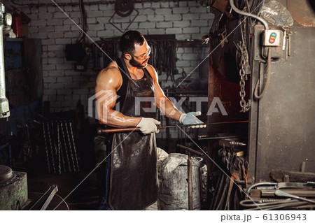 careful blacksmith holding metal in hands careful blacksmith holding metal in hands 61306943