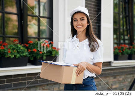 Crop of deliverywoman holding parcel and folder. Crop of deliverywoman holding parcel and folder. 61308828