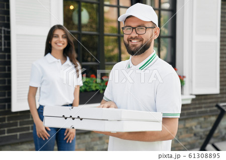Smiling deliveryboy holding boxes of pizza. 61308895