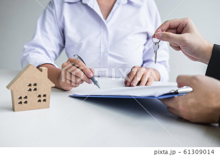 Estate agent giving house keys to client after 61309014