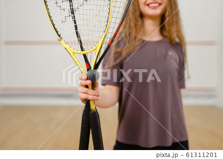Female person shows squash racket and ball 61311201