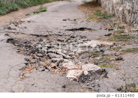 asphalt road destroyed by holes and washed out by 61311460