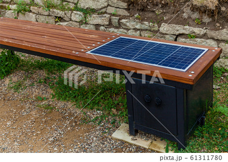 A wooden bench with a solar panel for charging a 61311780