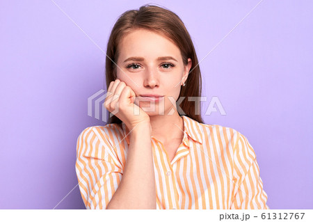 Cute female student keeps hand under chin, feels tired and bored at lesson 61312767
