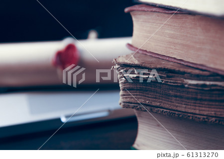 Book stack and laptop computer on workplace in library room with blurred bookshelf background, education concept 61313270
