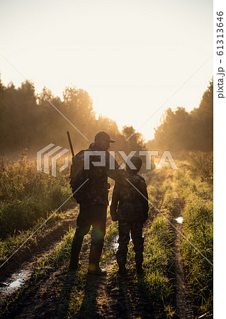 Father teaches his grandson to hunt in a woods 61313646