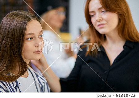 fashionable stylist doing make-up for young caucasian female 61318722