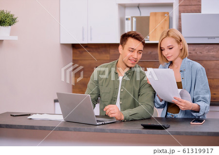 young happy couple sit with documents discuss about cash bills in the home kitchen young happy couple sit with documents discuss about cash bills in the home kitchen 61319917