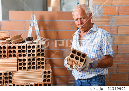 Man inspecting brick for installing wall 61319992