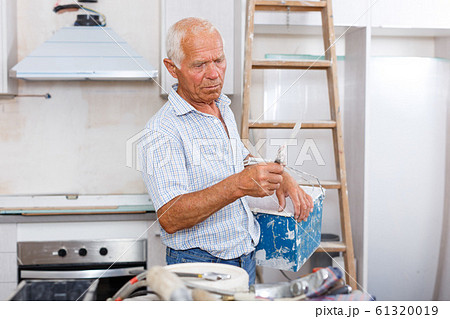 Senior man puttying walls Senior man puttying walls 61320019