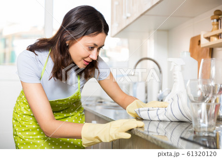 Girl housewife in apron cleaning furniture at kitchen at home Girl housewife in apron cleaning furniture at kitchen at home 61320120