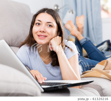 Young woman relaxing on sofa and using laptop at home Young woman relaxing on sofa and using laptop at home 61320216