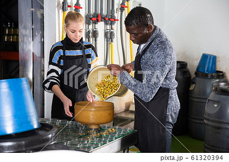 Couple filling glass jars with marinated olives Couple filling glass jars with marinated olives 61320394