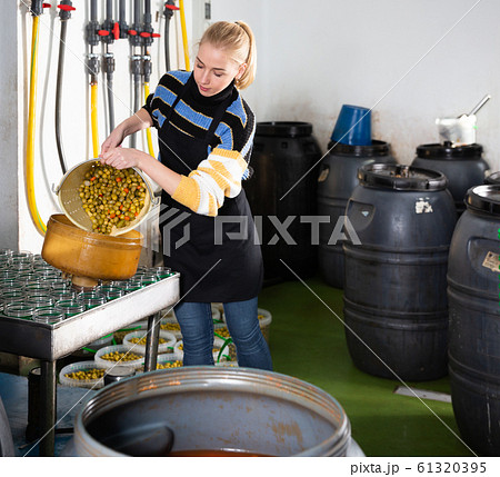 Woman prepares olives in glass jars for canning 61320395